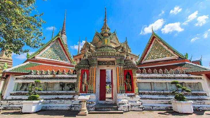 A building complex with colorful rooftops facing a fence with a detailed entrance