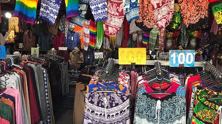 A market stall full of colourful pants and shirts on racks
