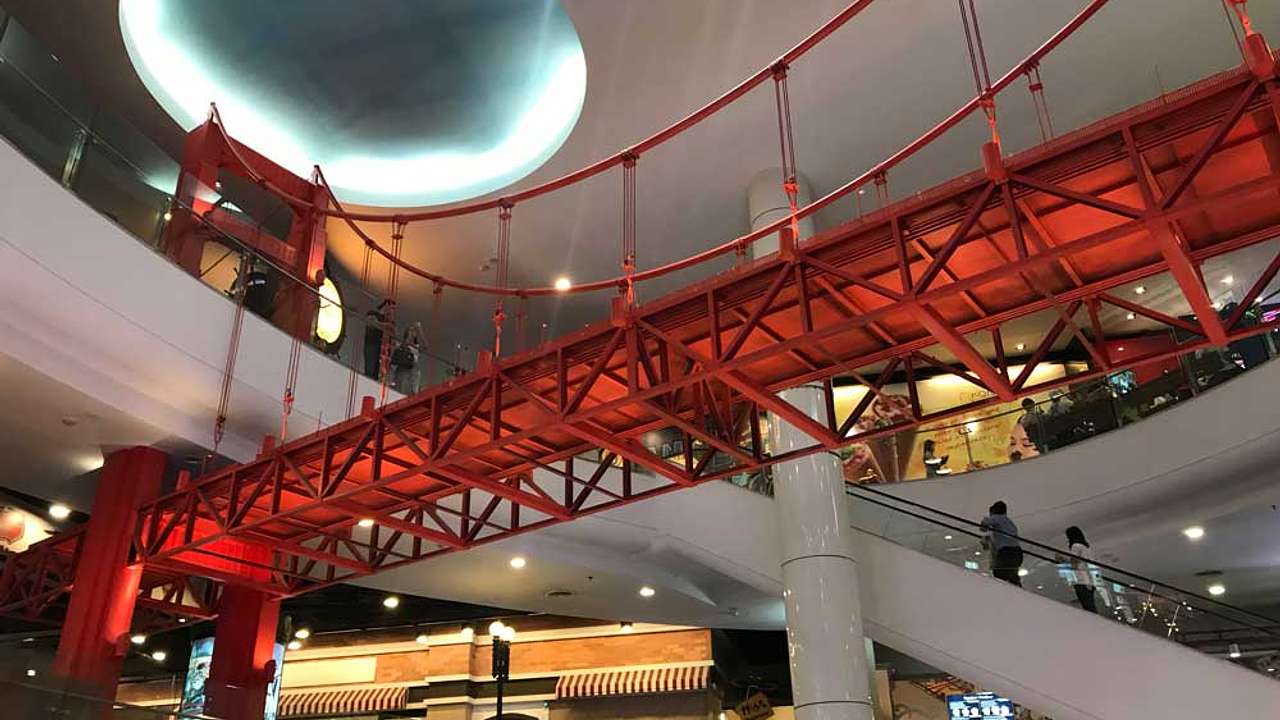 The inside of a shopping wall with a red bridge and an escalator at the back