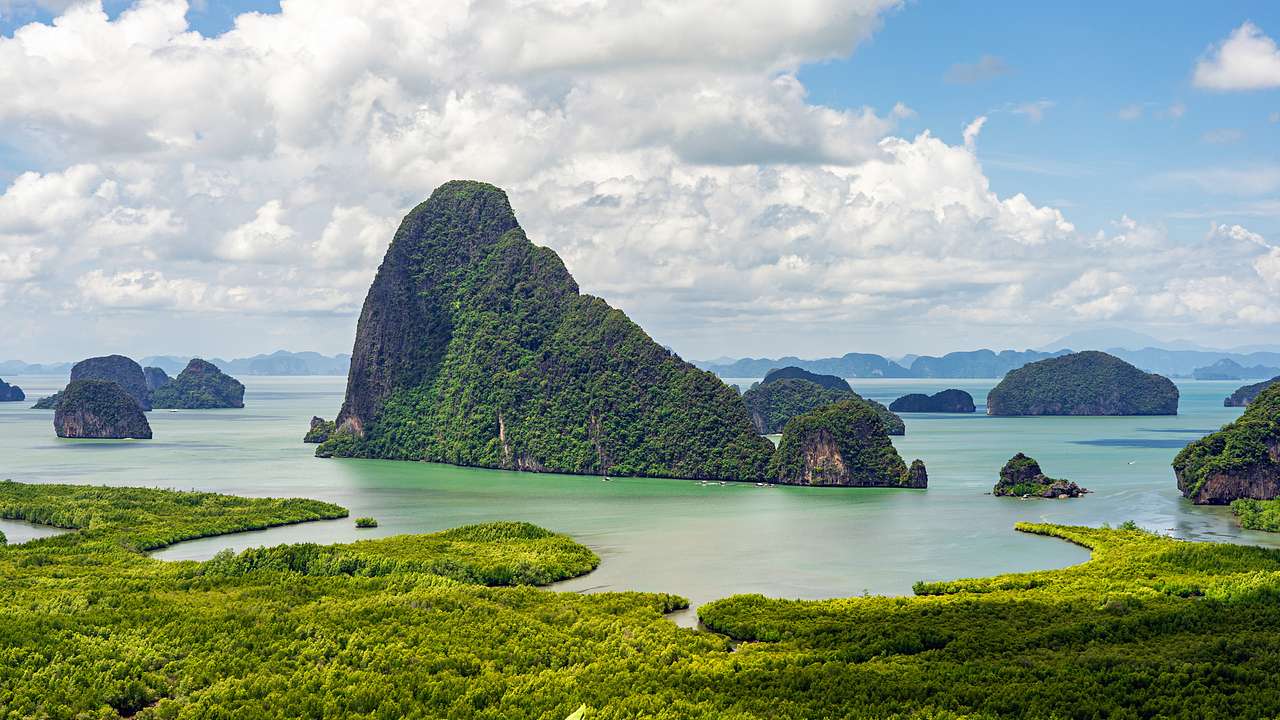 A group of islands in green water surrounded by other islands covered in greenery