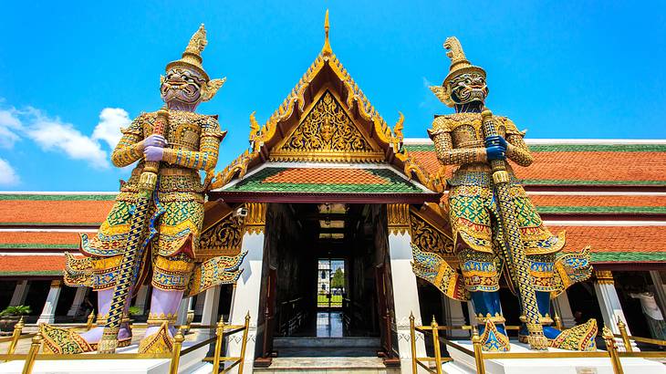 A gold temple with two large gold statues on both sides of the entrance