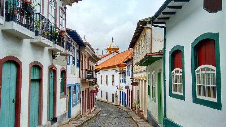 A paved street passing through baroque houses painted in multiple colors