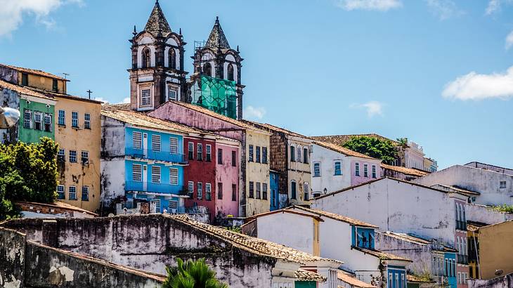 Brightly colored baroque houses with two flanking towers protruding in the background