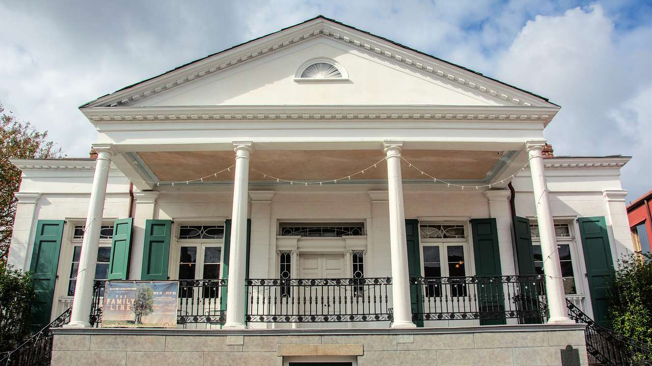 Looking up at a white building with white columns on a partly cloudy day