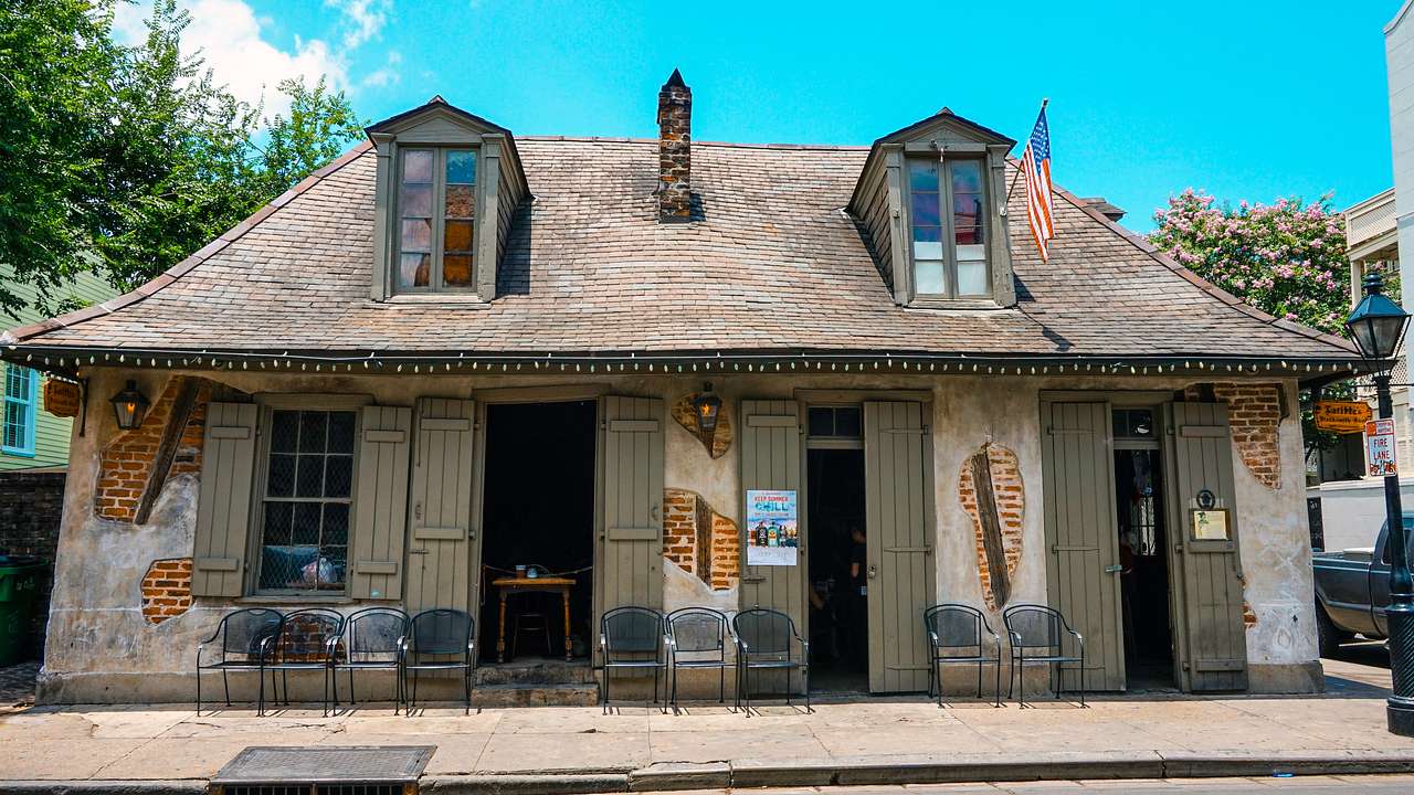 An old bricked house with chairs in front under a blue sky
