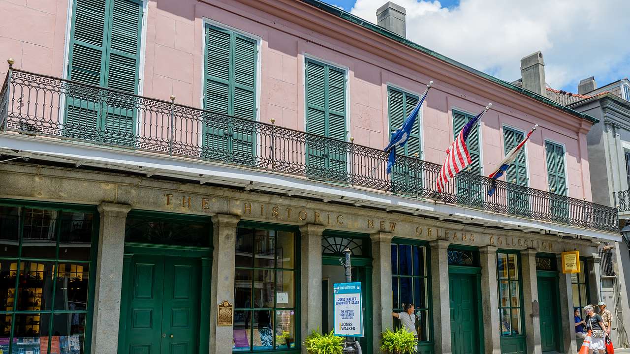 A green and pink building with hanging flags on its balcony