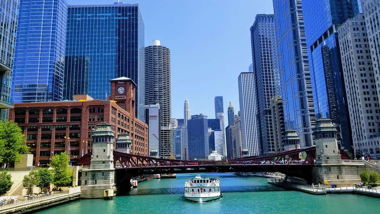 A riverboat cruise passing under a bridge, with skyscrapers on both sides