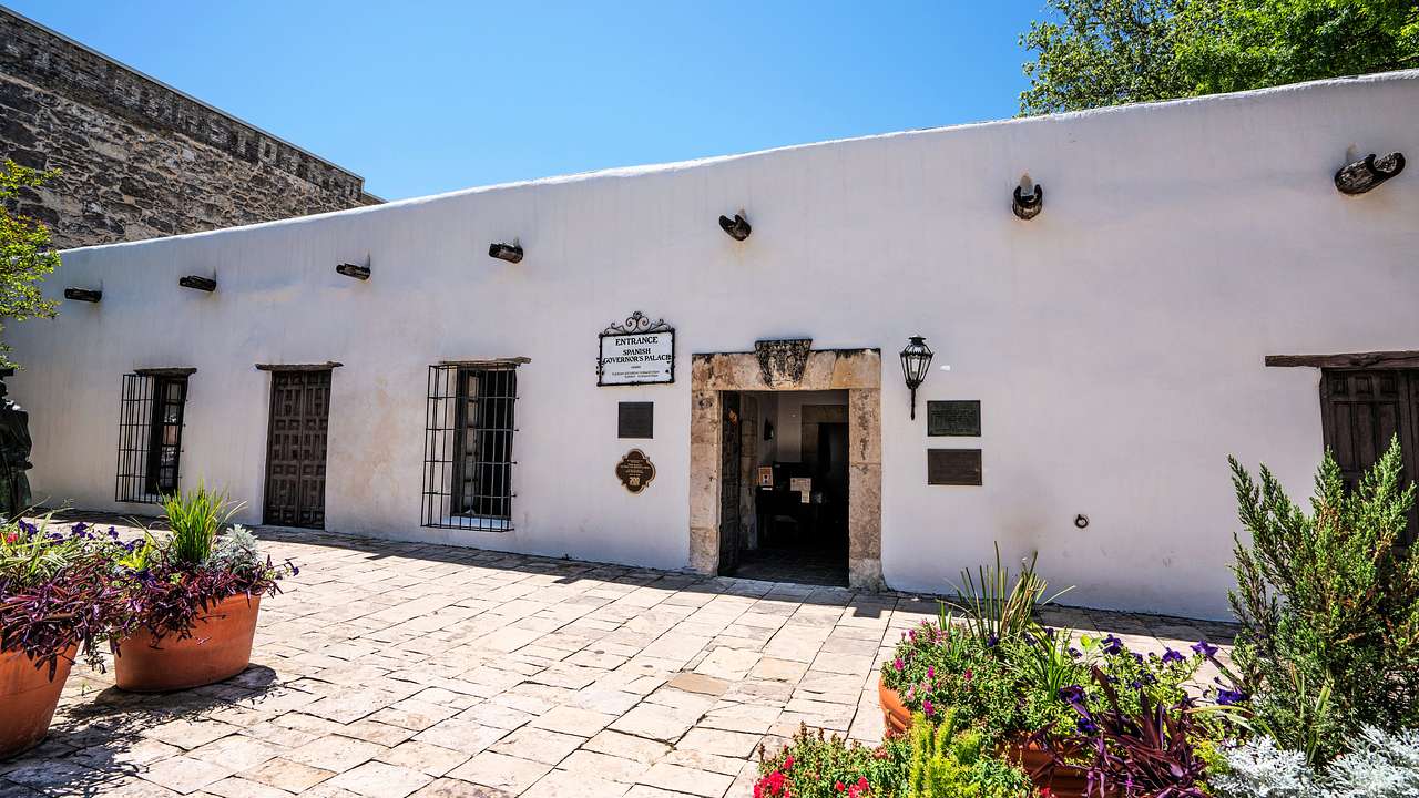 A Spanish Colonial-style home with a tiled patio with potted plants on it