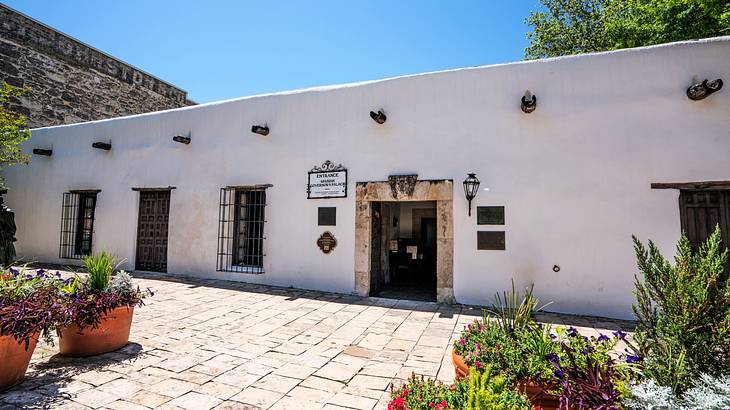 A Spanish Colonial-style home with a tiled patio with potted plants on it