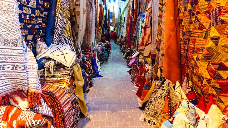 An alley lined with many colorful hanging and folded cloths