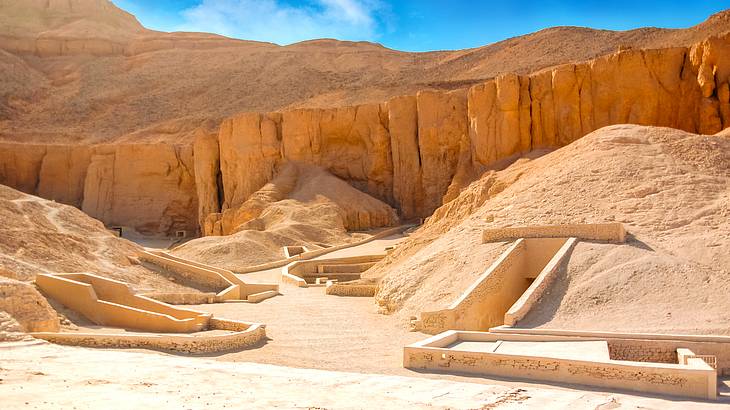 Ancient ruins carved into a desert cliffside on a beautiful sunny day with a blue sky