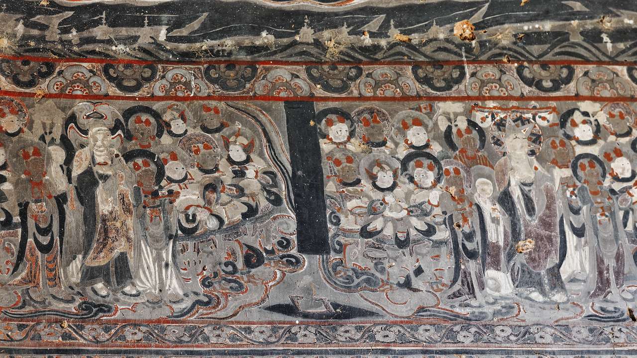 A cave wall painted with a picture of praying monks with halos