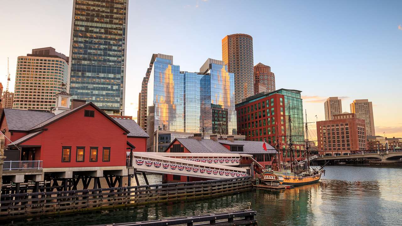 A boat docked at a pier with buildings and skyscrapers in the background