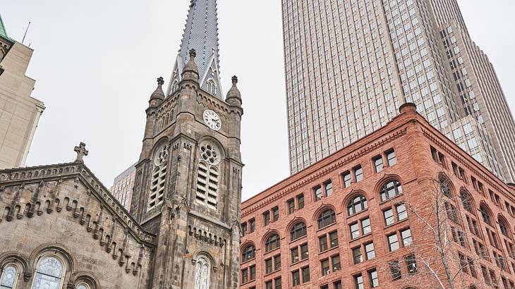 A stone church with a pointy tower and other modern buildings surrounding it