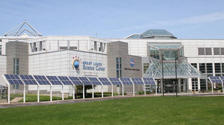 A white and glass museum building with green grass in front of it, under a blue sky