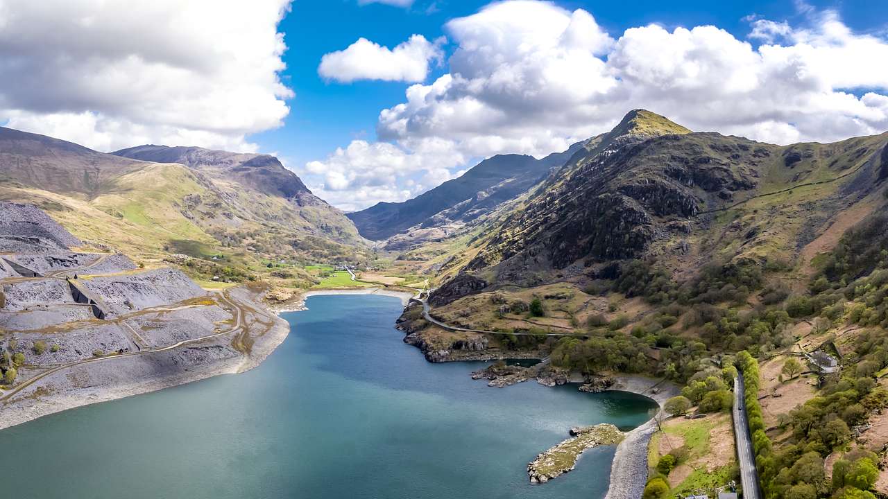 A wide-angle view of a lush green mountainous landscape with a green body of water