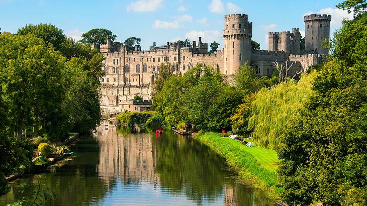 A canal with green trees on each side, flowing towards a castle at the back