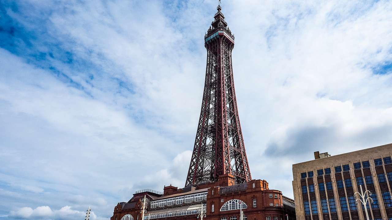 A red steel tower on top of a building, rising towards a partly cloudy sky