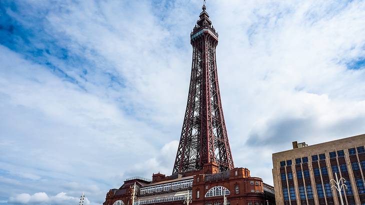 A red steel tower on top of a building, rising towards a partly cloudy sky