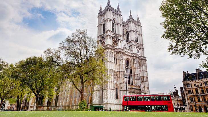 A bottom-up view of a beautiful cathedral with trees and a red bus in front