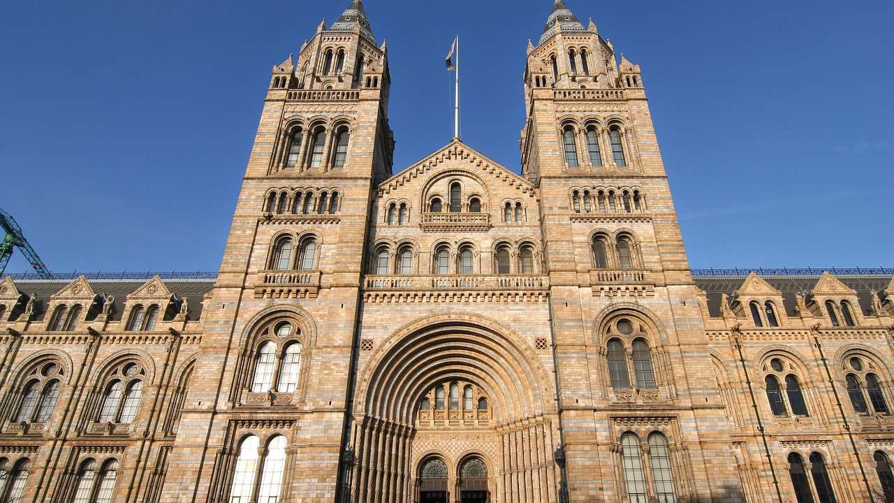 A large stone building with two spires and arched windows under a blue, cloudless sky