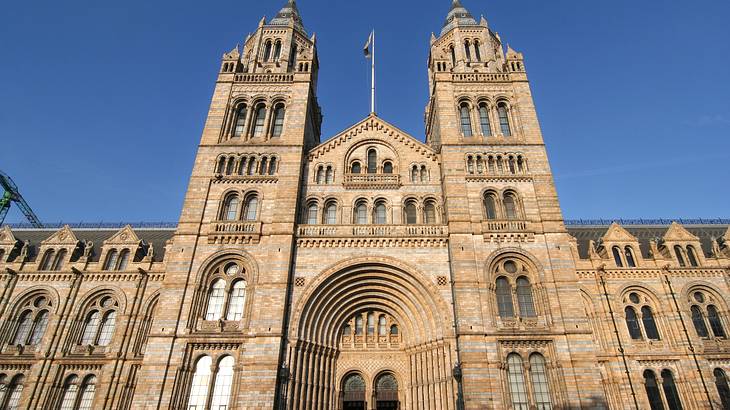 A large stone building with two spires and arched windows under a blue, cloudless sky