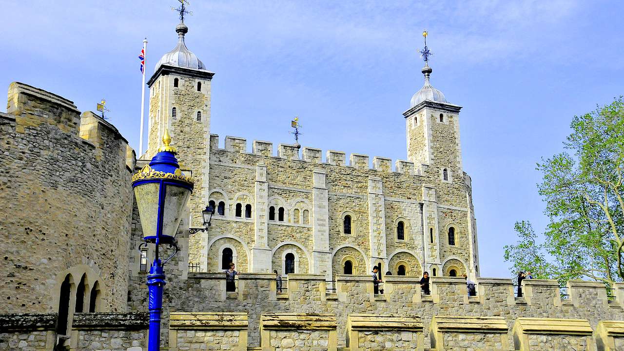 A historic fortress with a wall in front, from below, against a blue sky