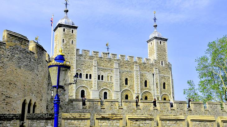 A historic fortress with a wall in front, from below, against a blue sky