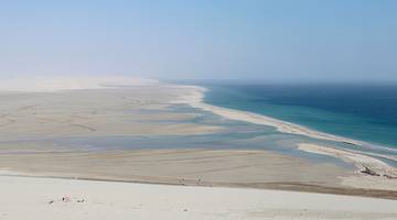 White sand dunes meet the vast, blue sea