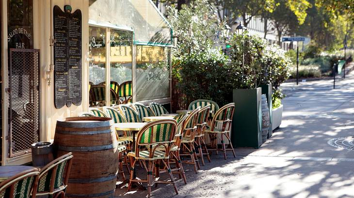 A restaurant with tables, cushions and chairs arranged along a street