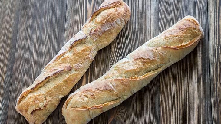 Two crunchy baguettes on a wooden background