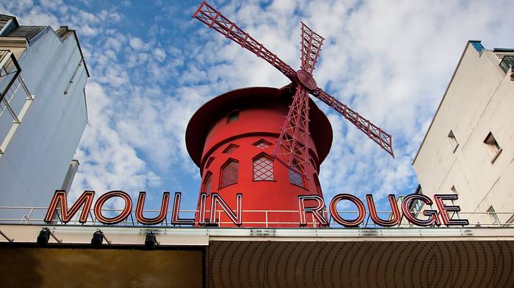 A bright red windmill protruding from the top of the Moulin Rouge building