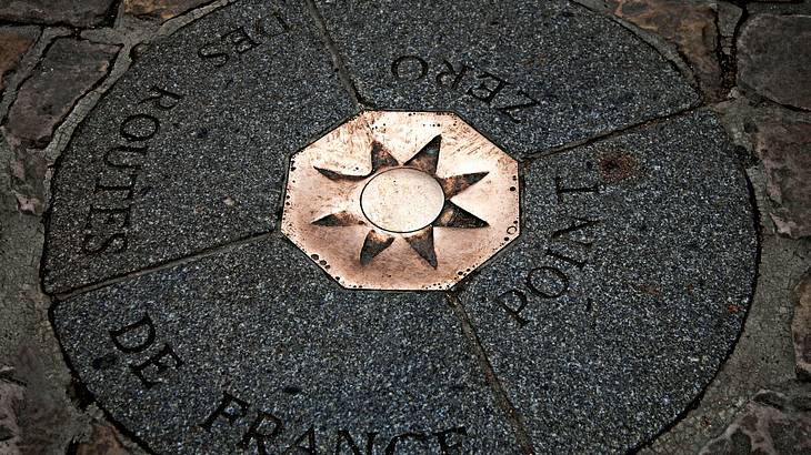 An up-close shot of a metallic, star shaped compass in the ground