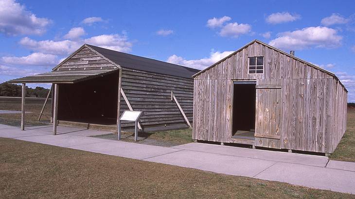 Two wooden barn-like buildings along pavement and grass