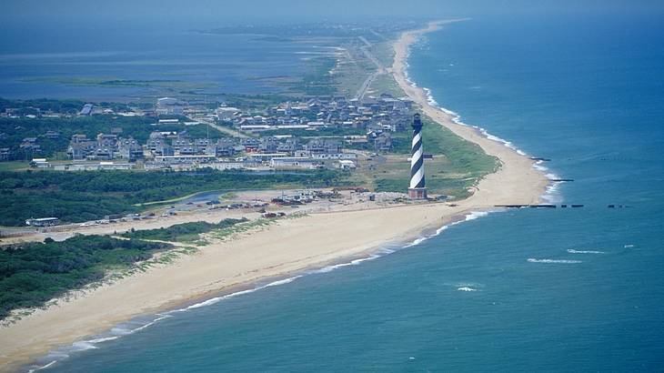 Aerial view of a lighthouse looking over a sandy coastline and ocean