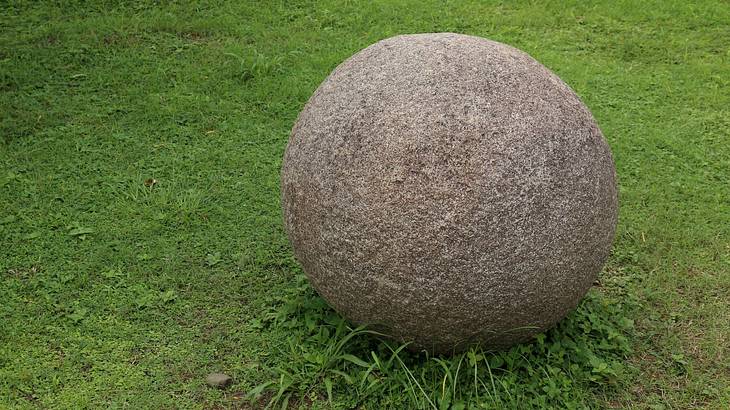 Mysterious stone sphere sitting on a green lawn