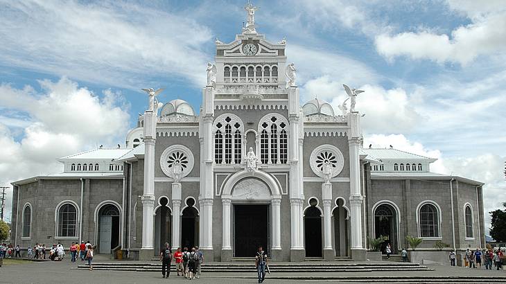 Front view of a white basilica with people in front on a sunny day