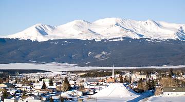 Snow-capped mountain peaks against blue sky with a town in front
