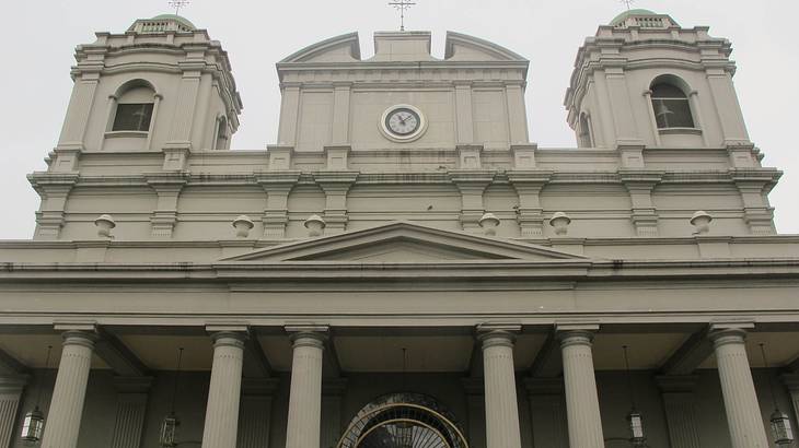 Front view of a church entrance with columns and a cloudy sky above