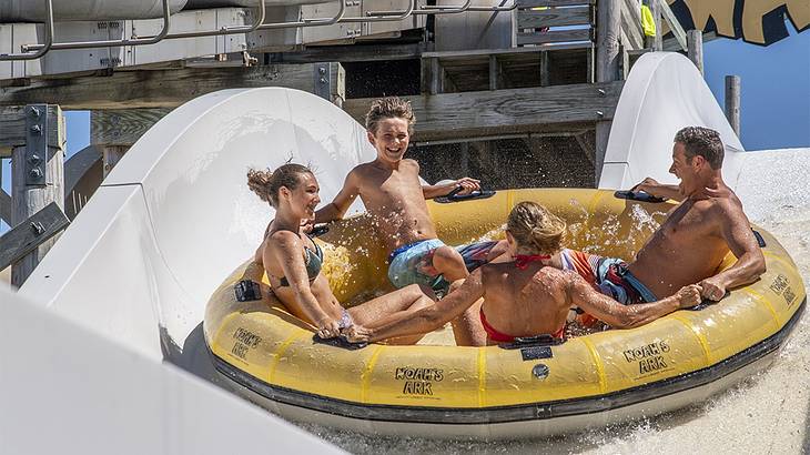 A family in a yellow circle tube going down a white water slide up close