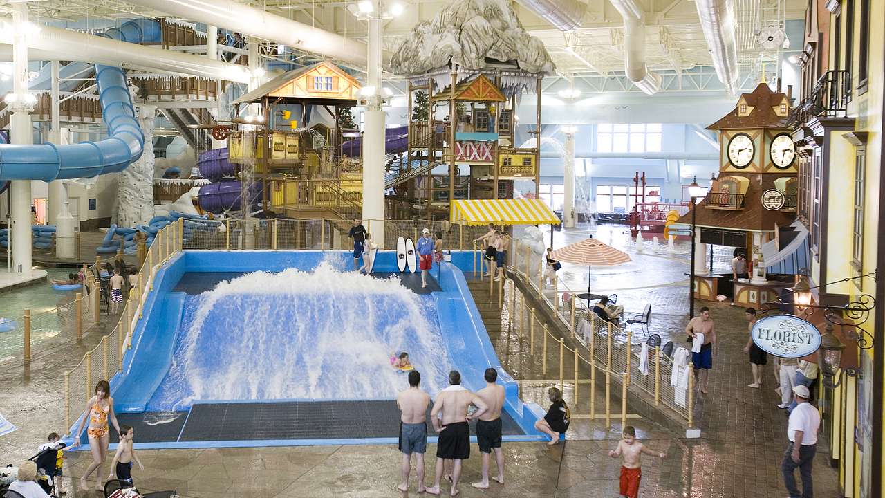 Aerial view of people standing around at an indoor waterpark with a blue water slide
