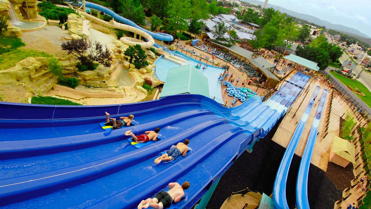 Aerial view of four people sliding down a large blue four-lane slide