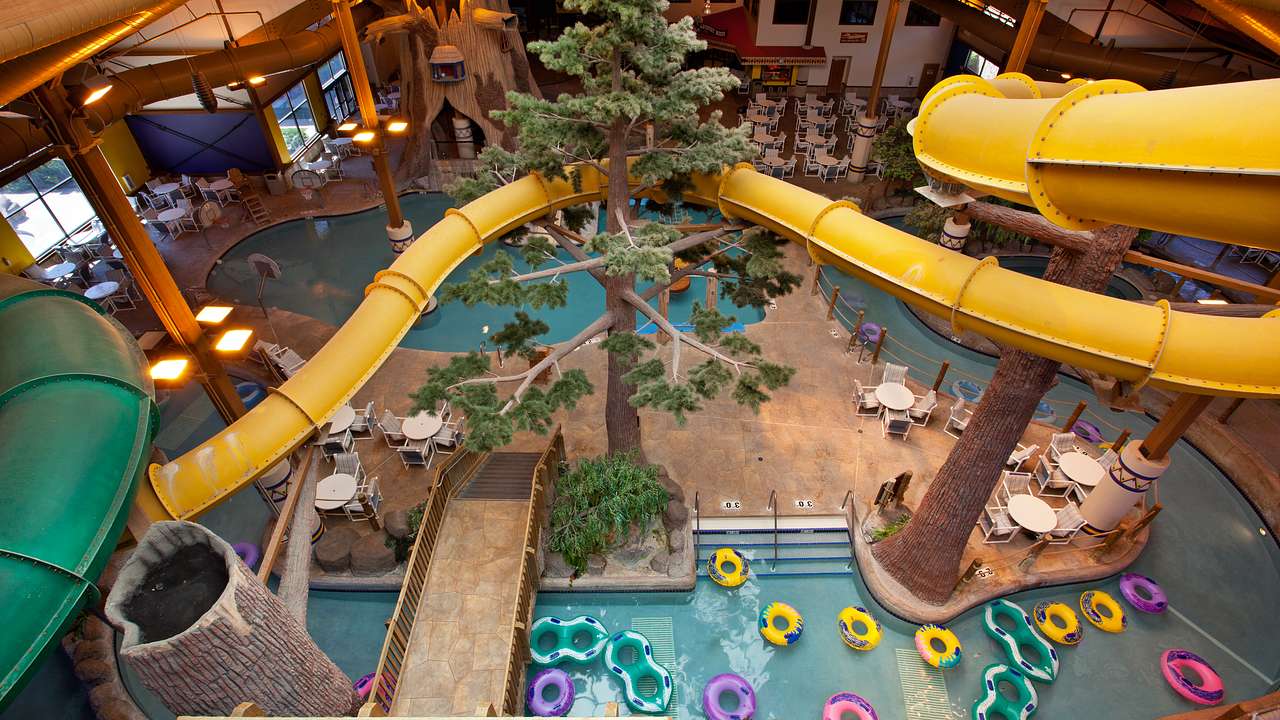 An aerial view of a long skinny yellow slide with pools below