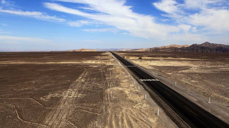 A road cutting through lines in the dirt in a desert from above