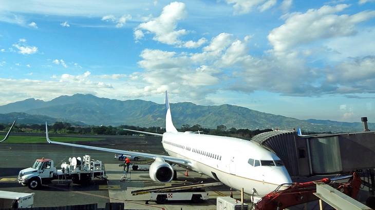 White aircraft parked on a tarmac with mountains in the background, on a sunny day