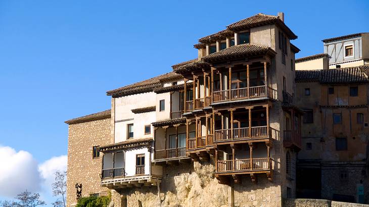 A building with multiple levels and balconies hanging off a cliff from below