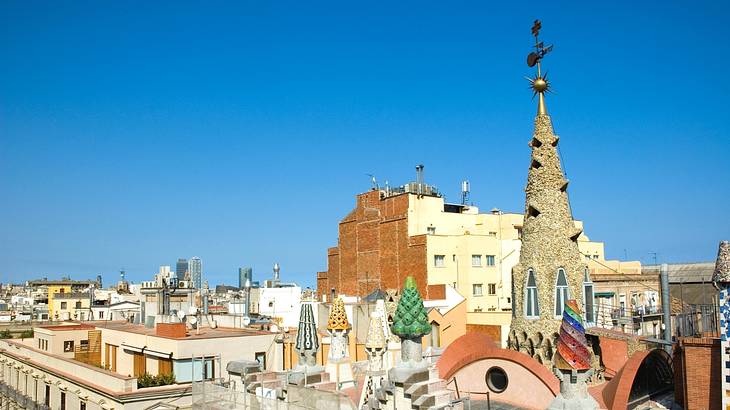 Top view over city buildings against blue sky, with a tall pointy roof on the right