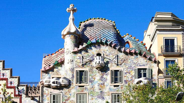 A stunning intricate colourful facade with a cross tower against blue sky