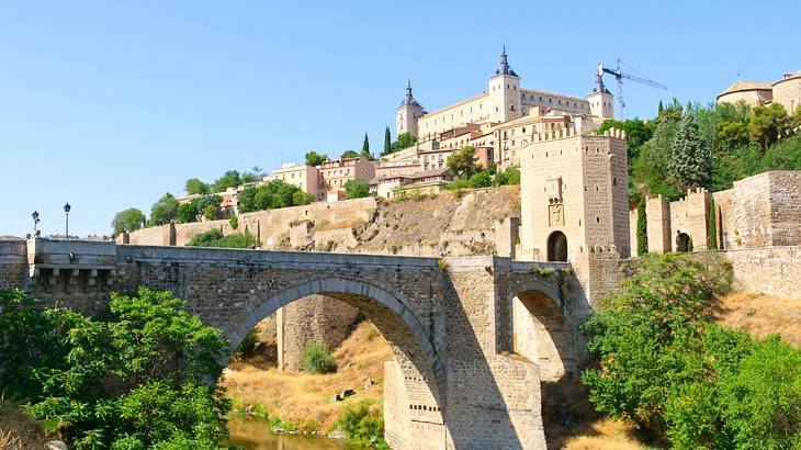 Looking up at a massive palace fortress on a hill with a bridge in front