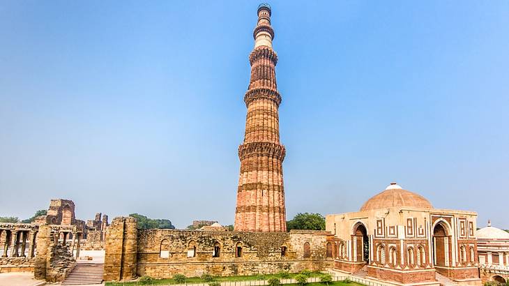 A tall tower structure made of bricks surrounded by ruined monuments